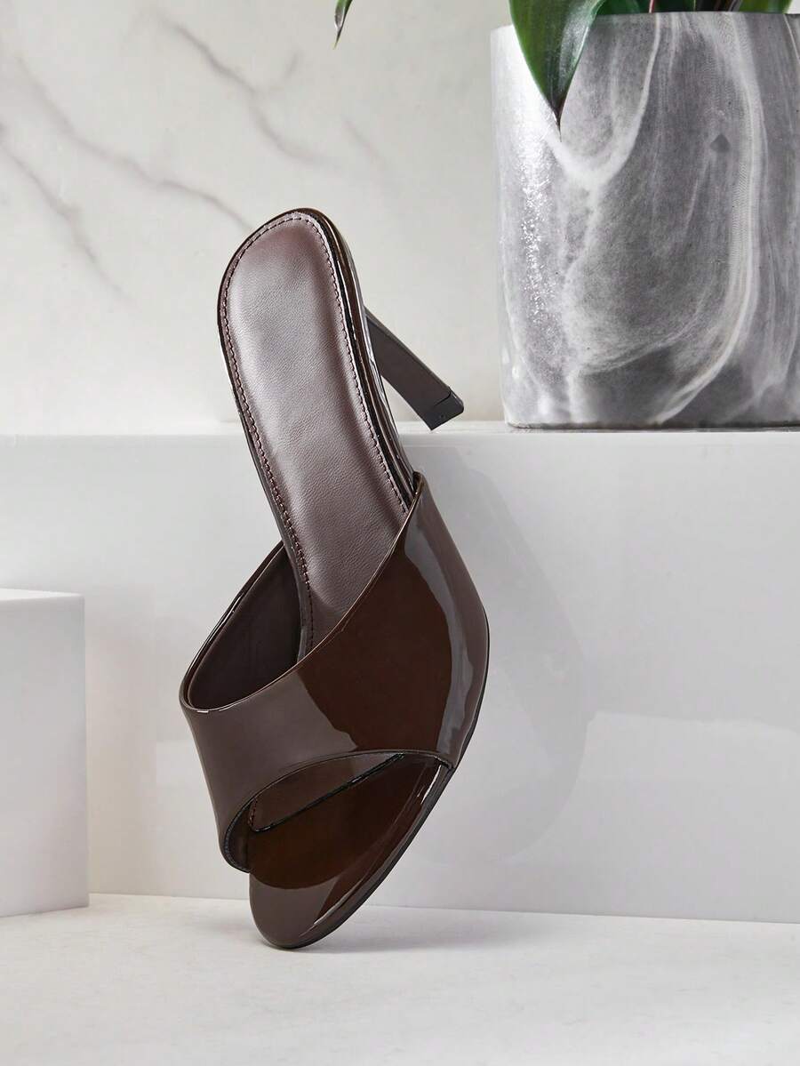 Black pointy toe kitten heel shoes for women featuring a sleek cut out mule design and glossy patent leather finish.