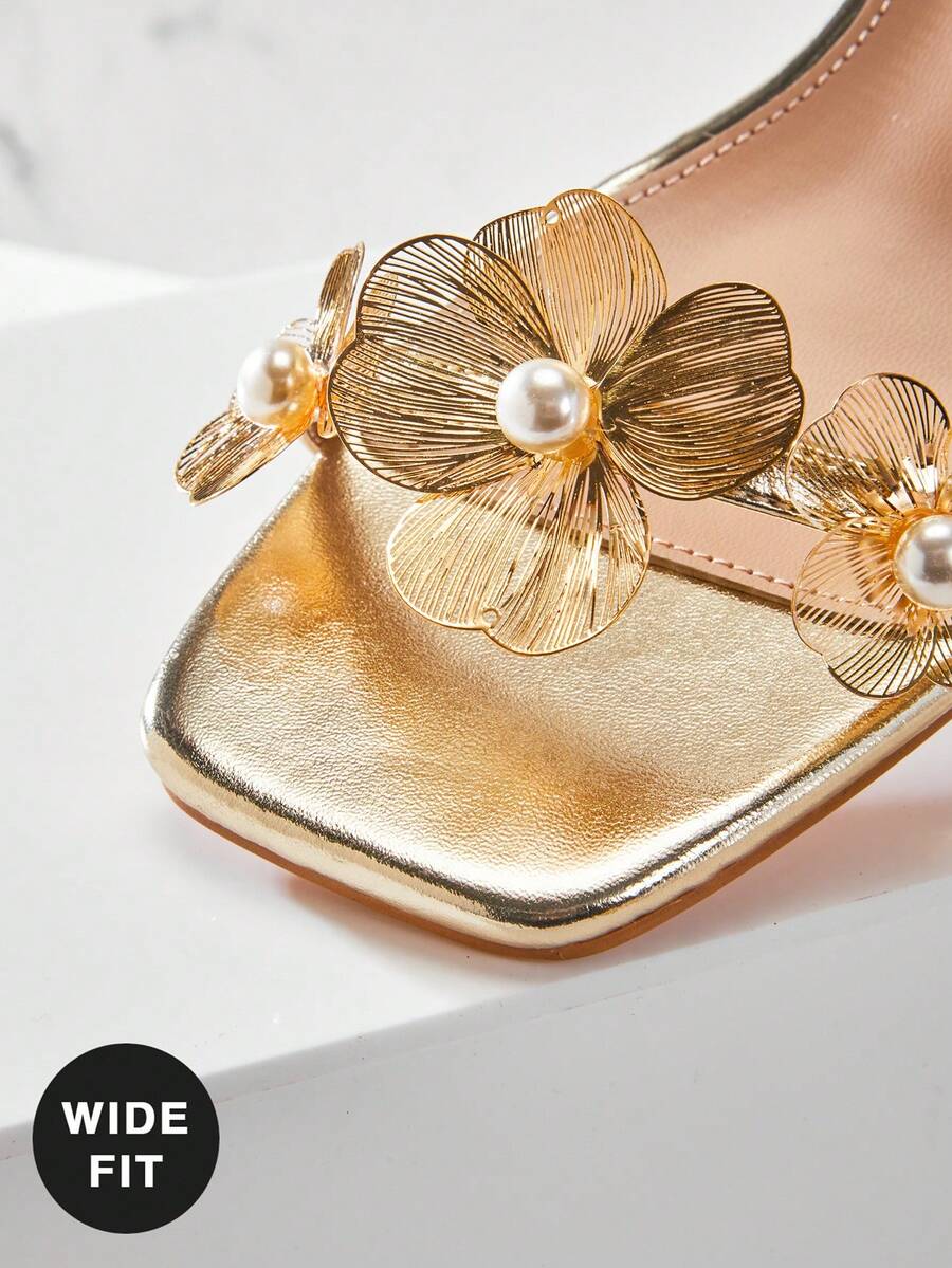 Women's metallic gold wide-fit high heeled sandals featuring stiletto heels, open toe straps, and elegant floral appliques.