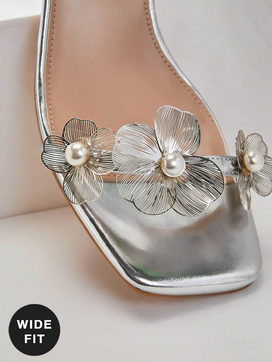 Women's metallic gold wide-fit high heeled sandals featuring stiletto heels, open toe straps, and elegant floral appliques.