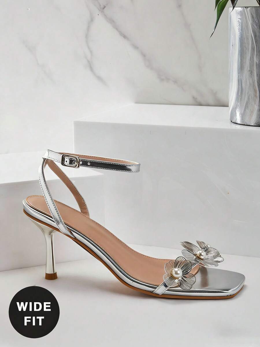 Women's metallic gold wide-fit high heeled sandals featuring stiletto heels, open toe straps, and elegant floral appliques.