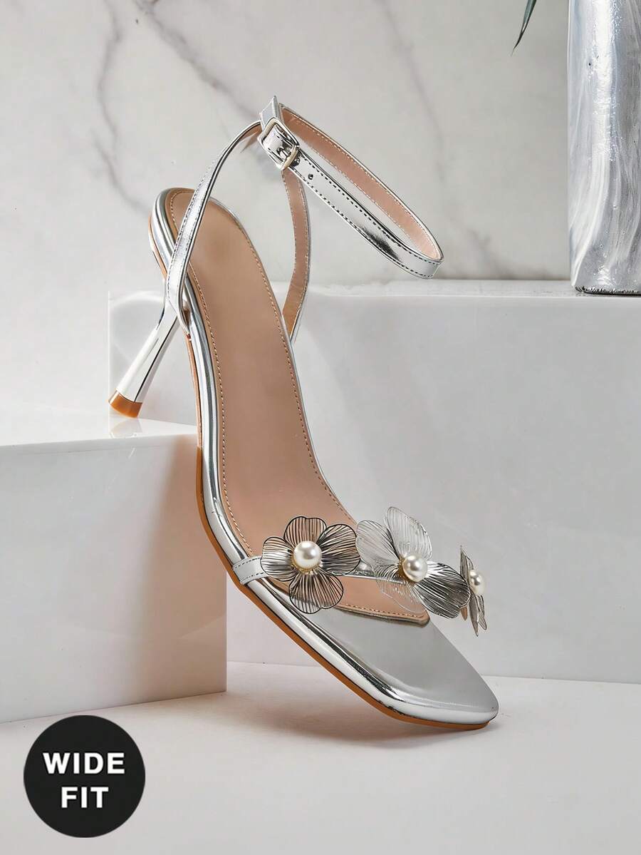 Women's metallic gold wide-fit high heeled sandals featuring stiletto heels, open toe straps, and elegant floral appliques.