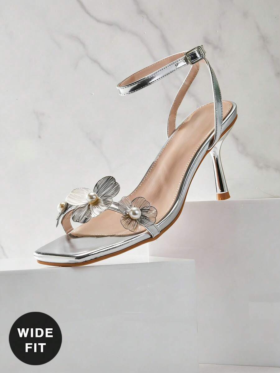 Women's metallic gold wide-fit high heeled sandals featuring stiletto heels, open toe straps, and elegant floral appliques.