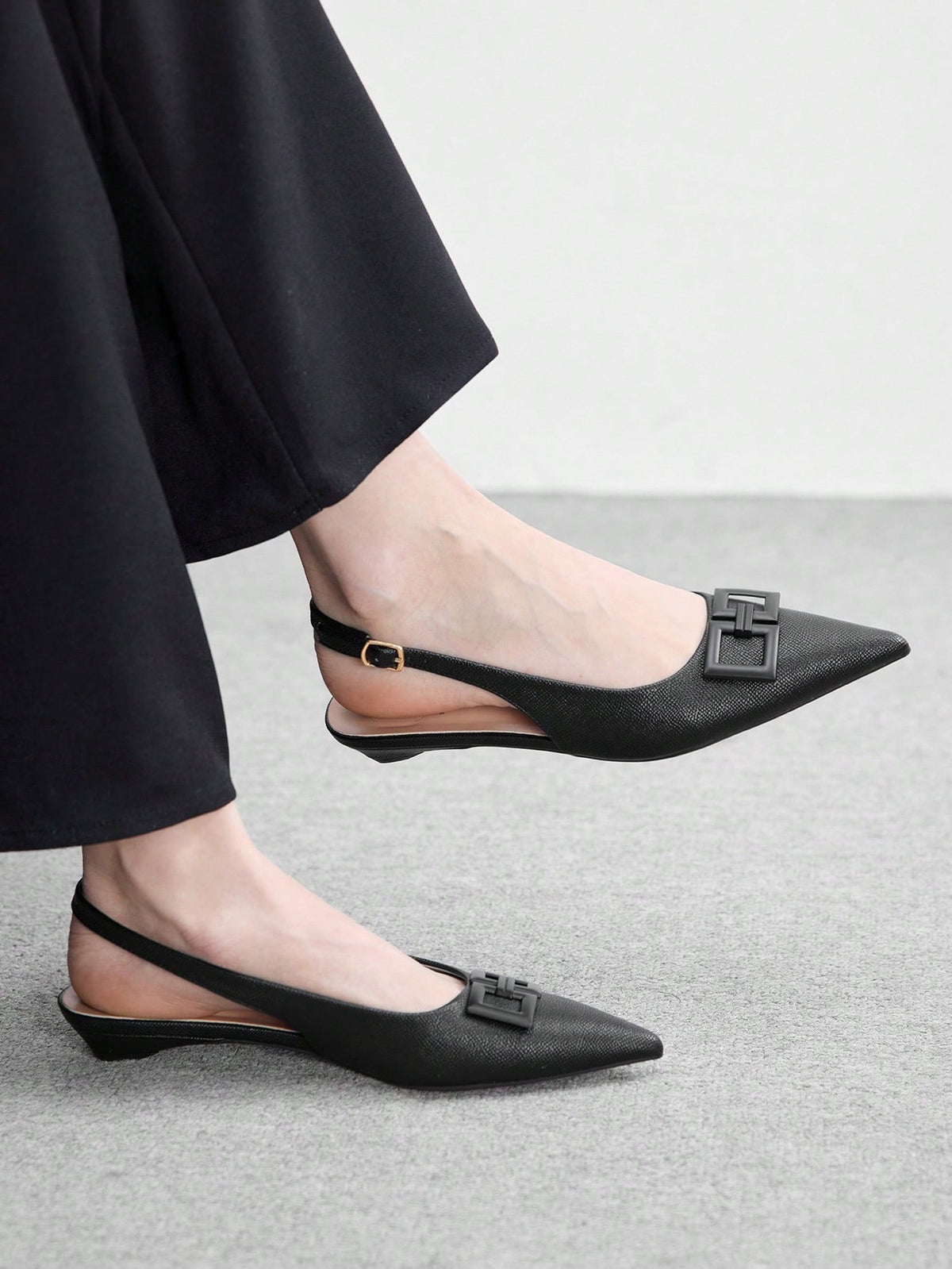 Women's pointed toe low wedge flat shoes crafted in PU leather with a slingback strap and stylish metal buckle detail.