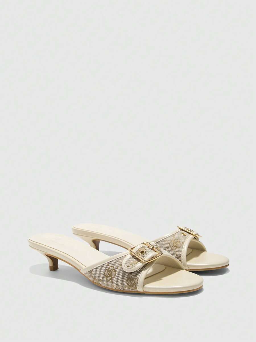 Beige women's slip-on kitten heel slide sandals featuring an accent buckle with grommet eyelets.
