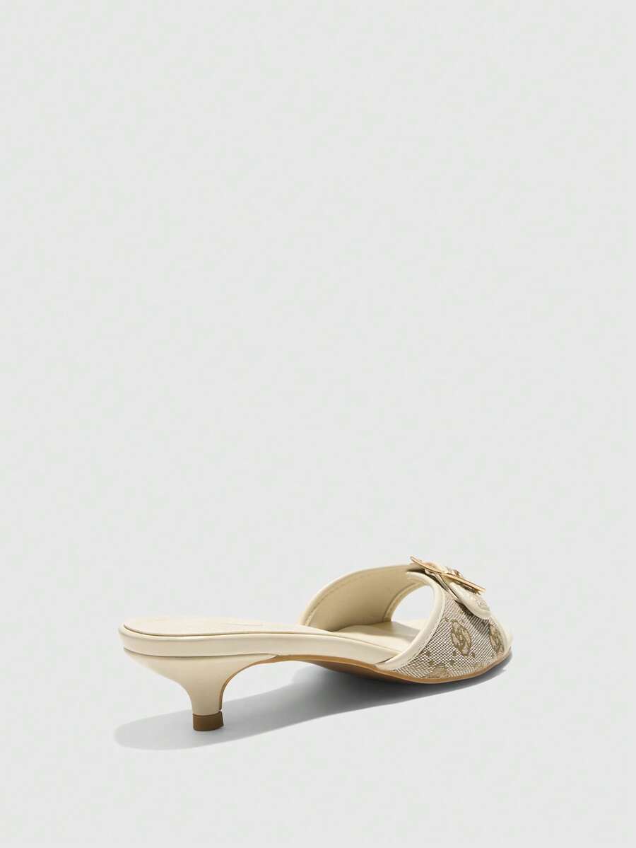 Beige women's slip-on kitten heel slide sandals featuring an accent buckle with grommet eyelets.