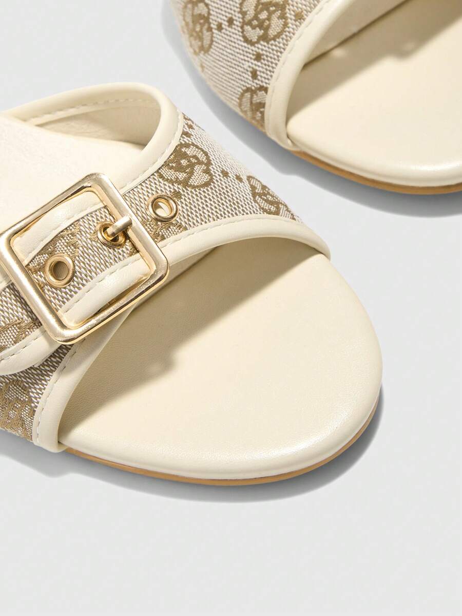 Beige women's slip-on kitten heel slide sandals featuring an accent buckle with grommet eyelets.