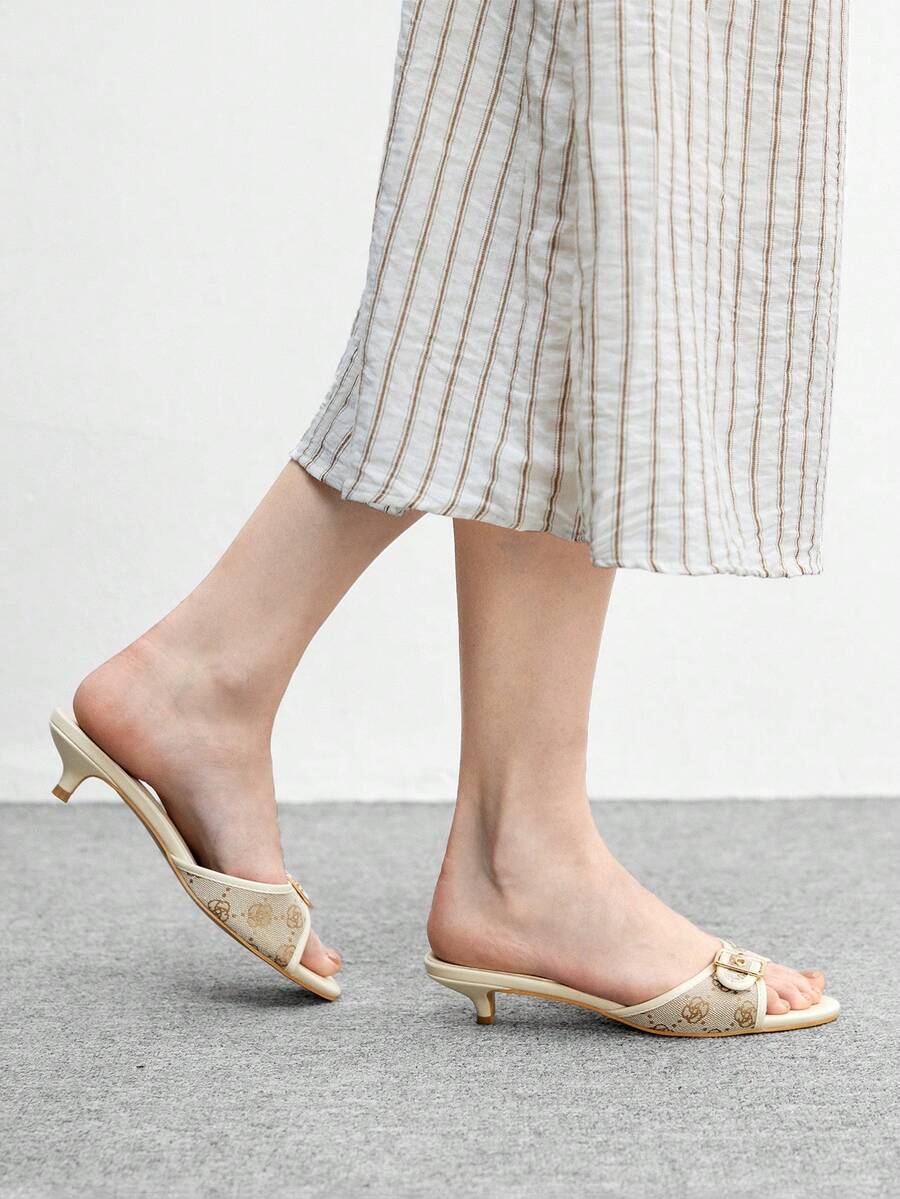 Beige women's slip-on kitten heel slide sandals featuring an accent buckle with grommet eyelets.