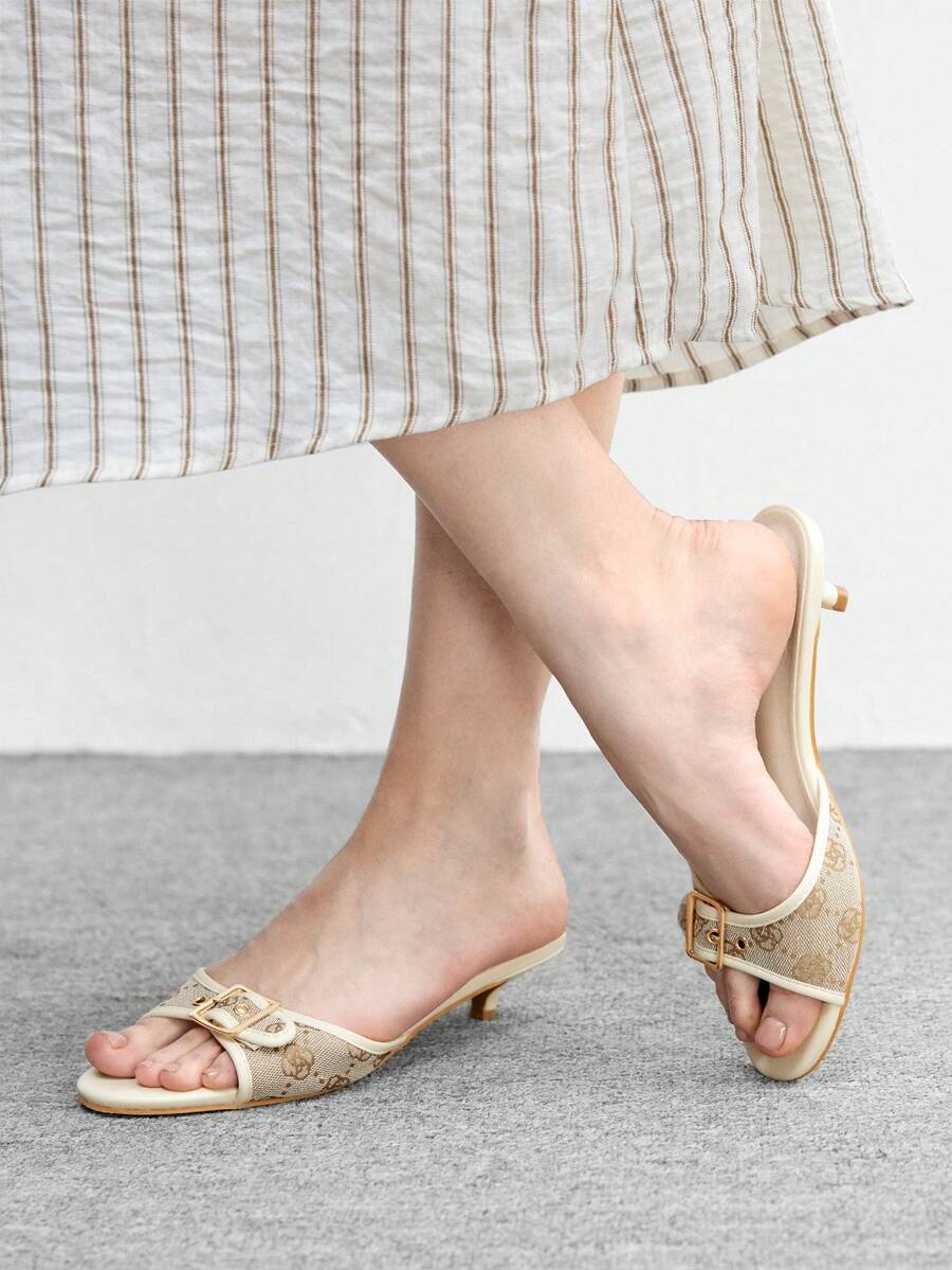 Beige women's slip-on kitten heel slide sandals featuring an accent buckle with grommet eyelets.