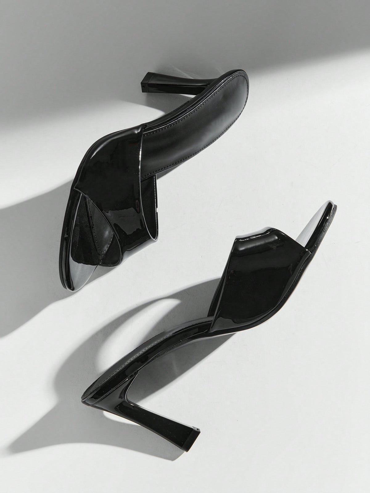 Black pointy toe kitten heel shoes for women featuring a sleek cut out mule design and glossy patent leather finish.