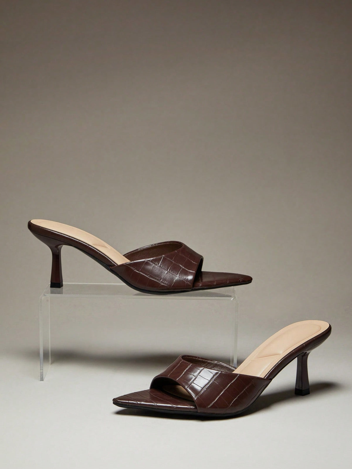 Black pointy toe kitten heel shoes for women featuring a sleek cut out mule design and glossy patent leather finish.