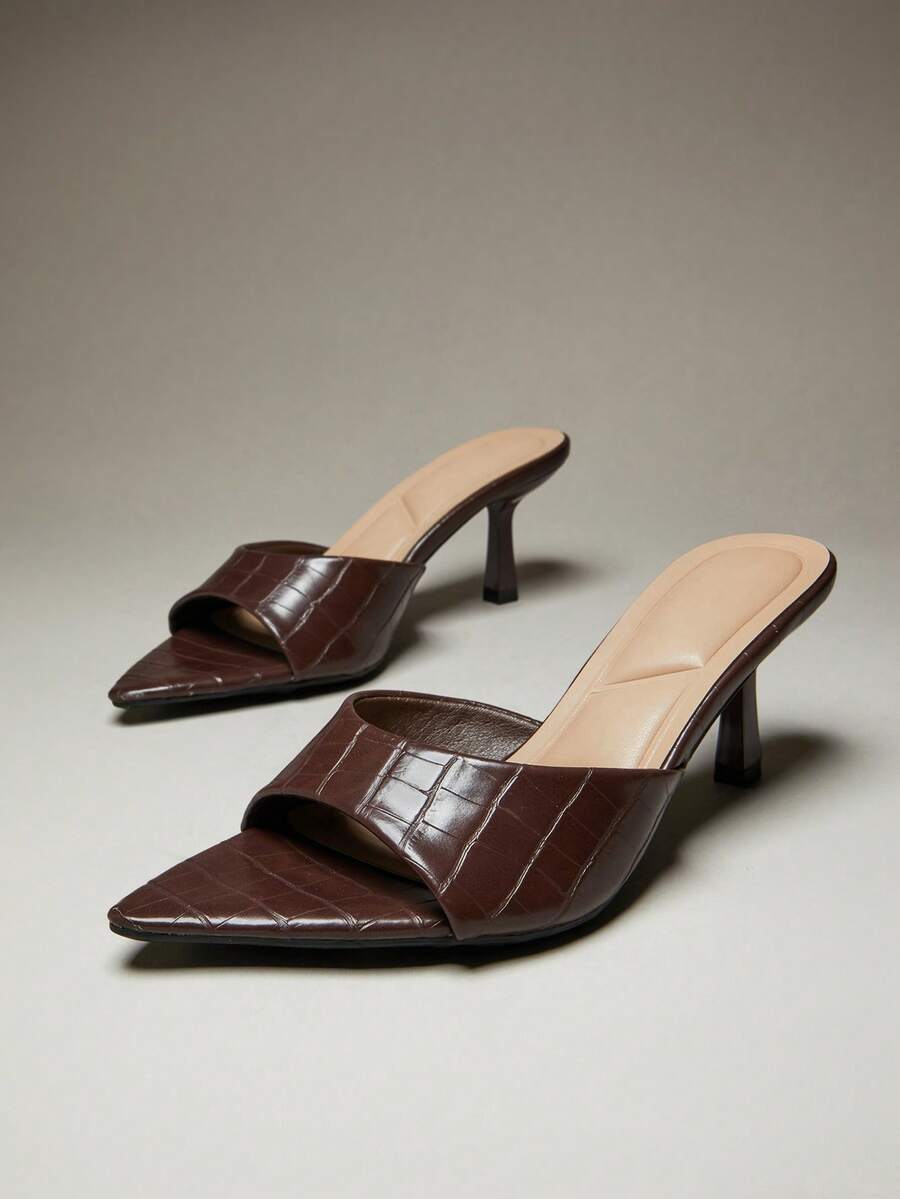Black pointy toe kitten heel shoes for women featuring a sleek cut out mule design and glossy patent leather finish.