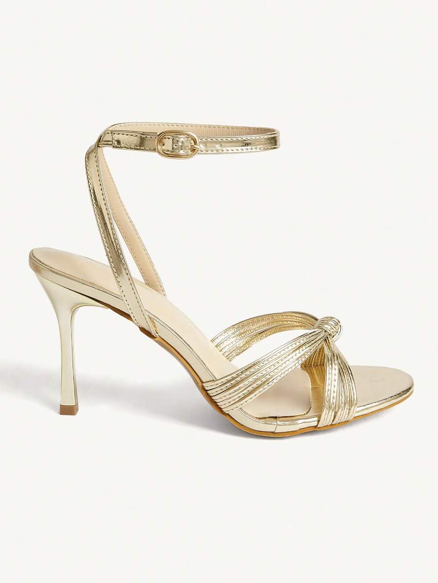 Women's champagne stiletto high heel sandals featuring knotted cross-over straps, open round toe, and adjustable ankle buckle strap.