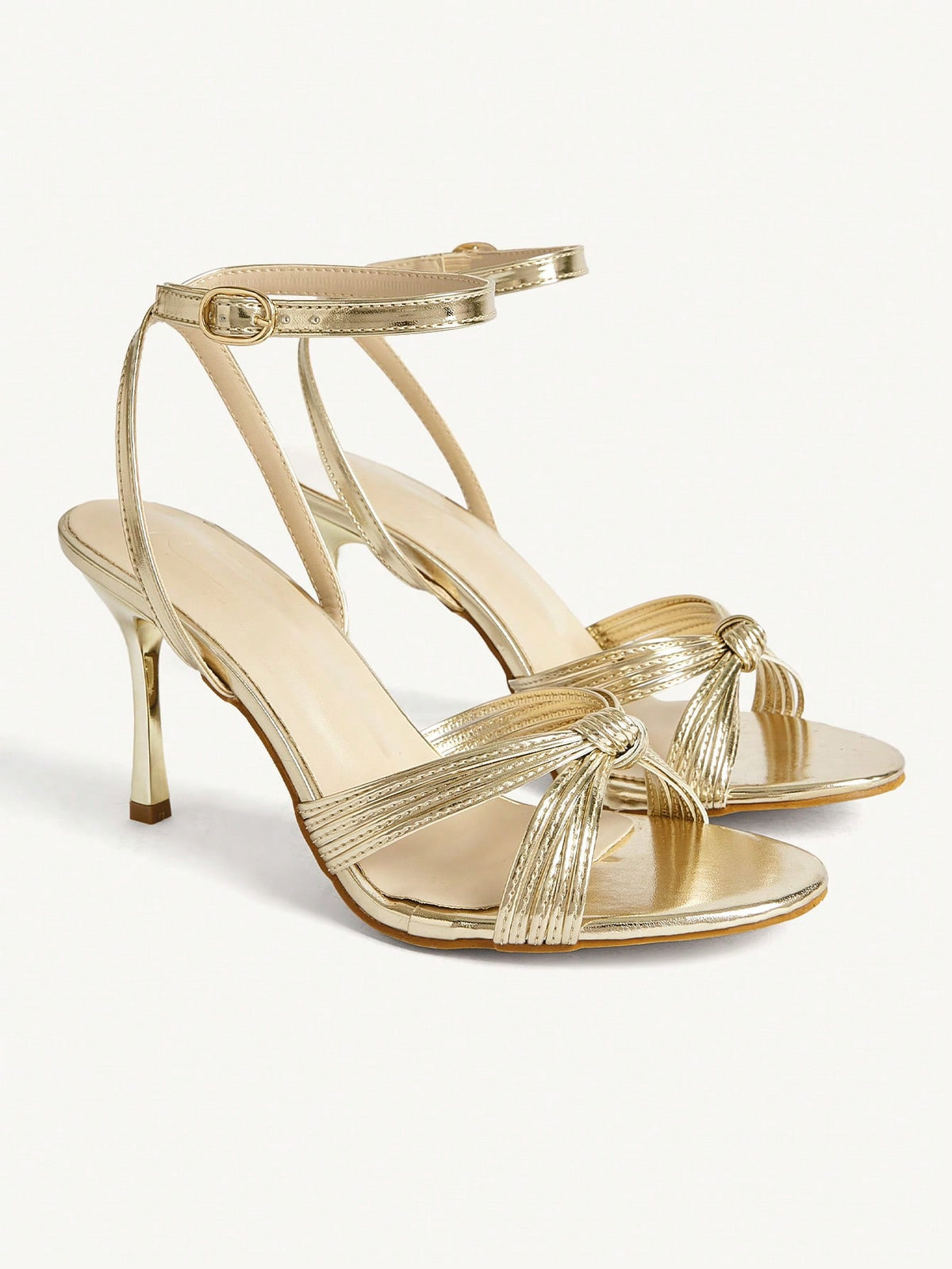 Women's champagne stiletto high heel sandals featuring knotted cross-over straps, open round toe, and adjustable ankle buckle strap.