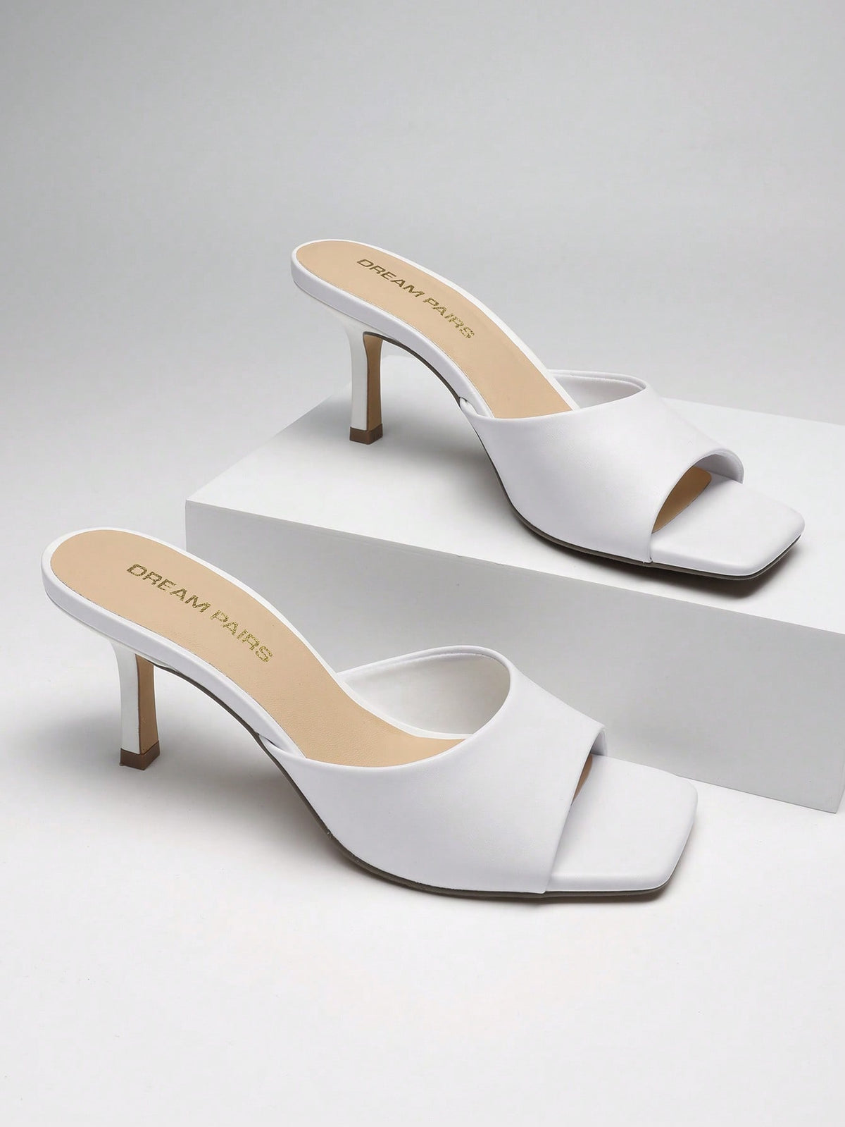 Pair of women's open square toe kitten heel mule sandals in white PU leather with slip-on styling.