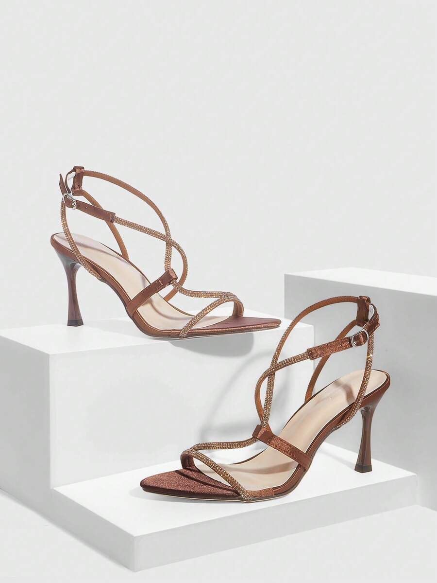 Women's pointed toe high heel sandals embellished with sparkling rhinestones, stiletto heels, and ankle strap buckle closure.