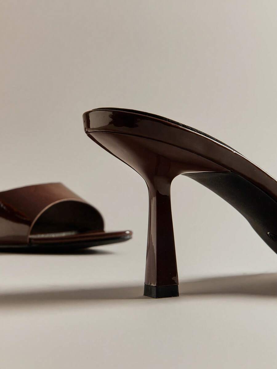 Pair of women's minimalist black pointy toe stiletto heel sandals with slingback straps.