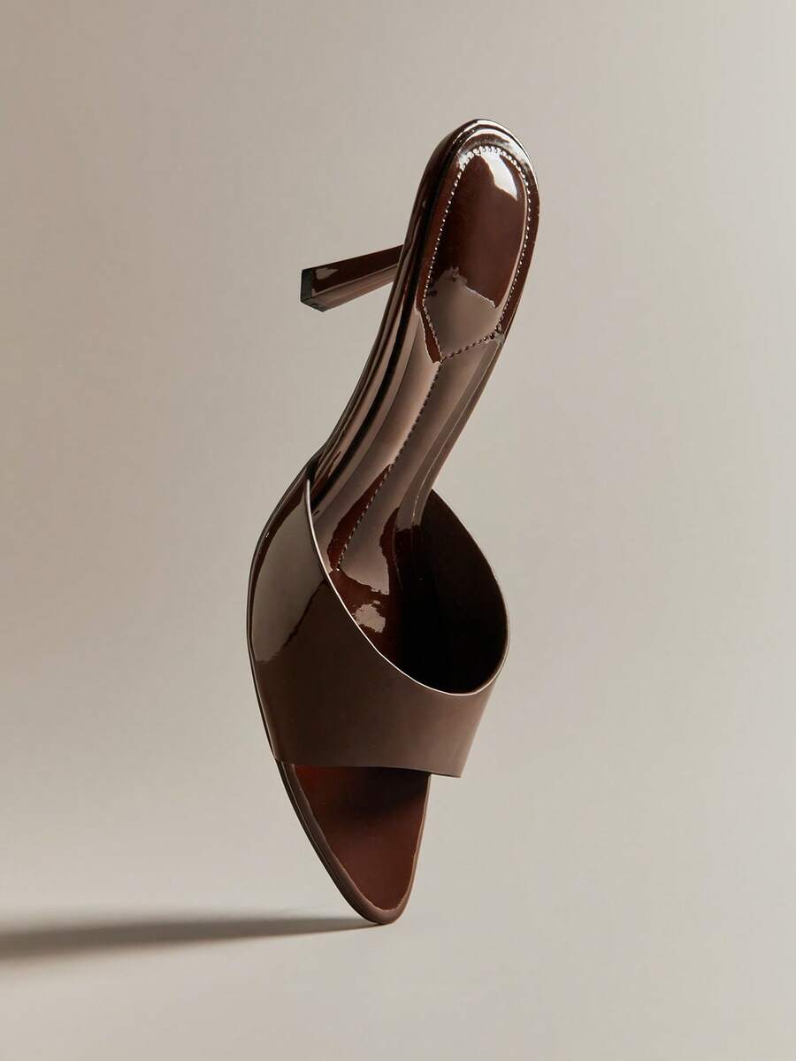 Pair of women's minimalist black pointy toe stiletto heel sandals with slingback straps.