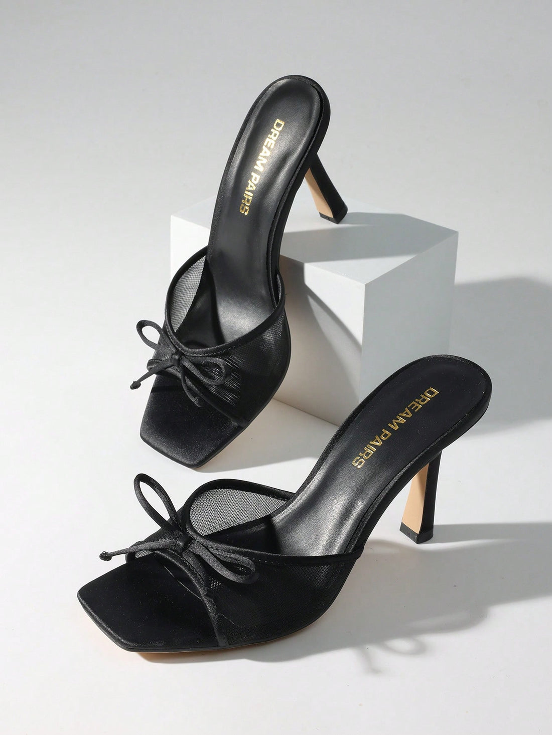 Women's open toe stiletto mule sandals featuring a breathable mesh upper with a decorative bow and square toe design.