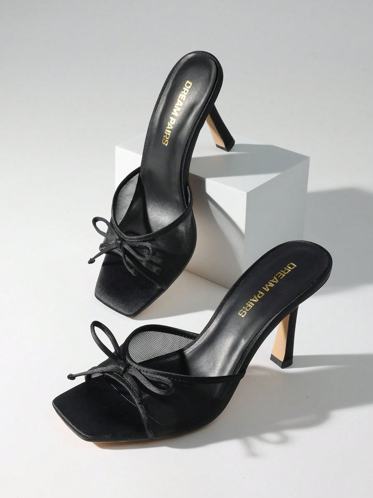 Women's open toe stiletto mule sandals featuring a breathable mesh upper with a decorative bow and square toe design.