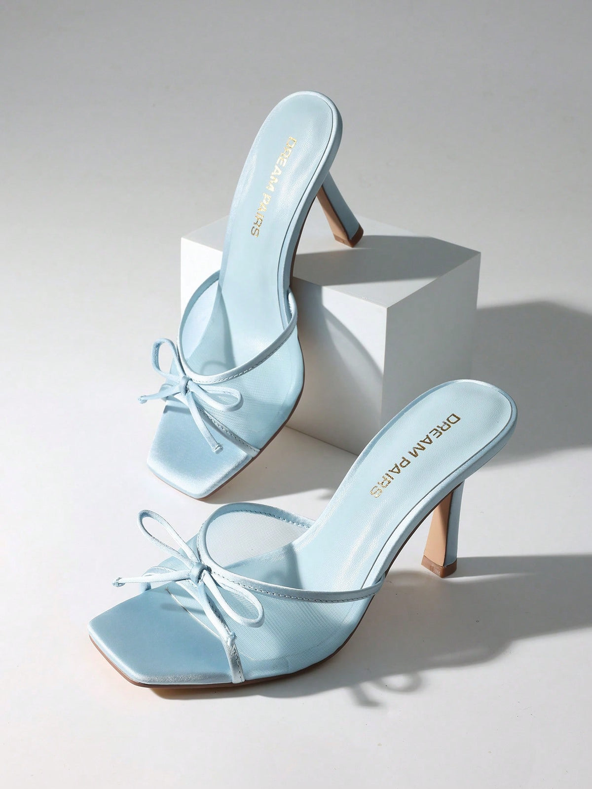 Women's open toe stiletto mule sandals featuring a breathable mesh upper with a decorative bow and square toe design.