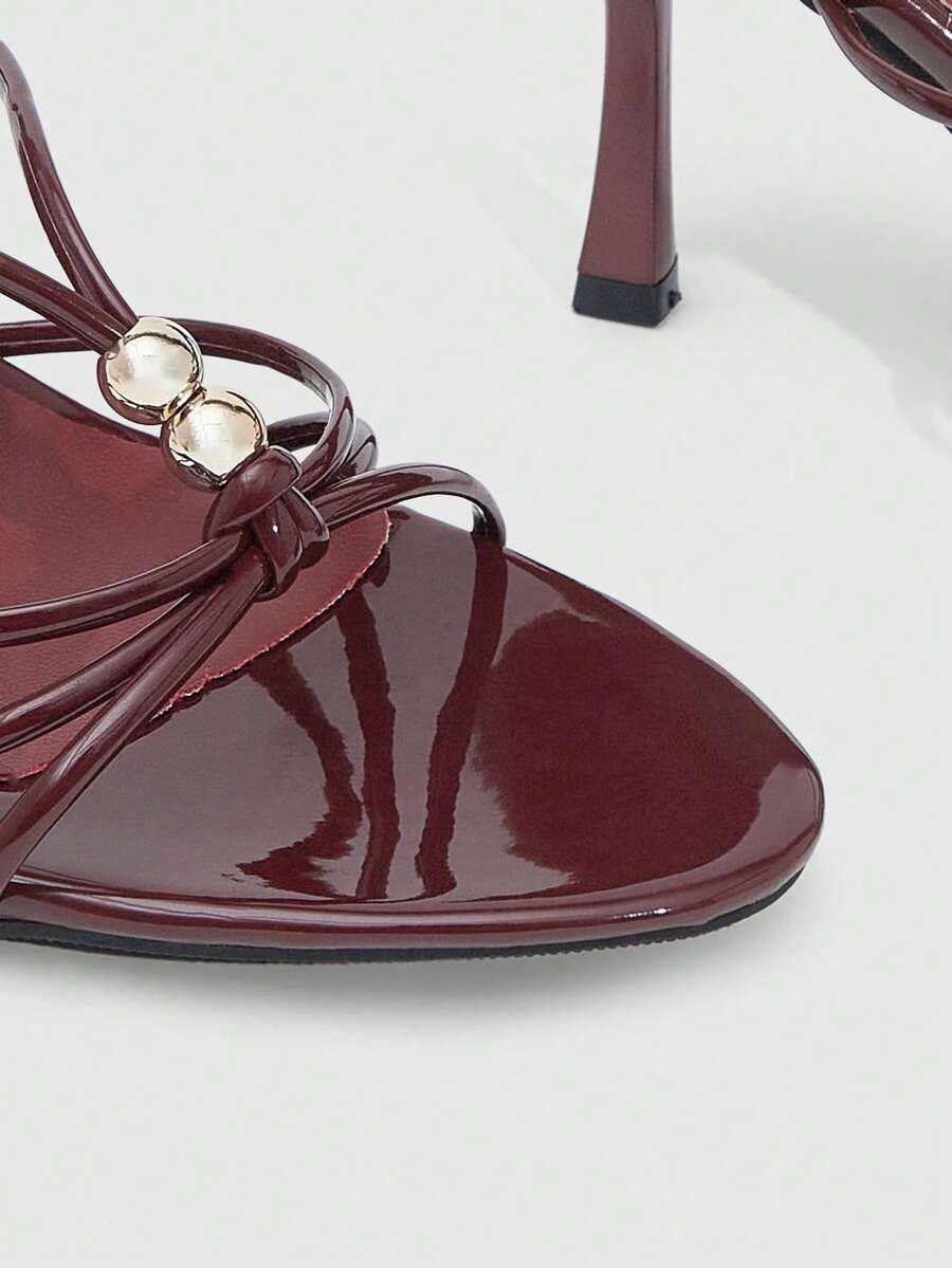 Burgundy stiletto high heel sandals featuring open toe thin straps and knot details