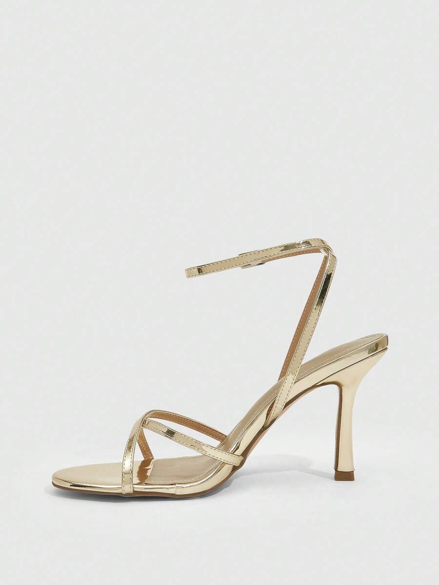 Pair of cream open-toe heeled sandals featuring crisscross front straps, a sleek stiletto high heel, and an adjustable ankle strap with buckle closure.