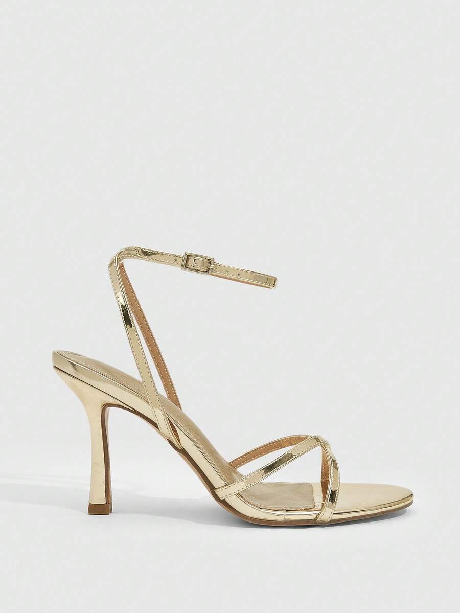 Pair of cream open-toe heeled sandals featuring crisscross front straps, a sleek stiletto high heel, and an adjustable ankle strap with buckle closure.