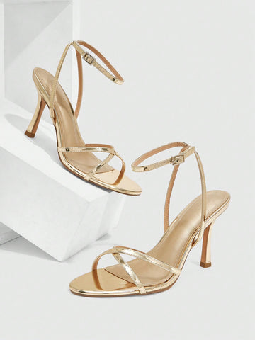 Pair of cream open-toe heeled sandals featuring crisscross front straps, a sleek stiletto high heel, and an adjustable ankle strap with buckle closure.