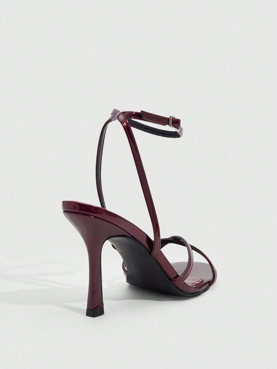 Pair of cream open-toe heeled sandals featuring crisscross front straps, a sleek stiletto high heel, and an adjustable ankle strap with buckle closure.