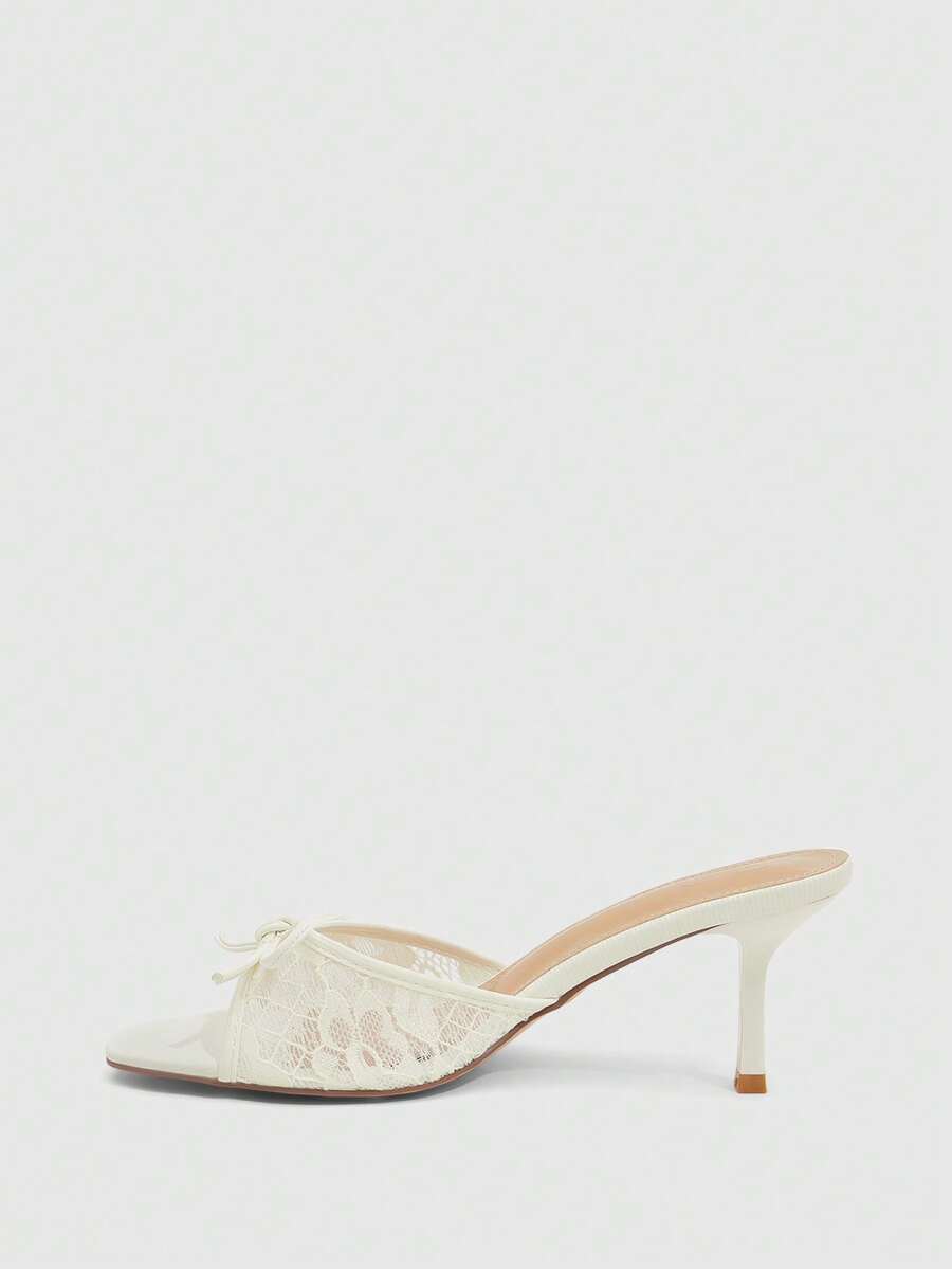 Open toe high heel slide sandals featuring lace details and a bow accent on the upper strap.