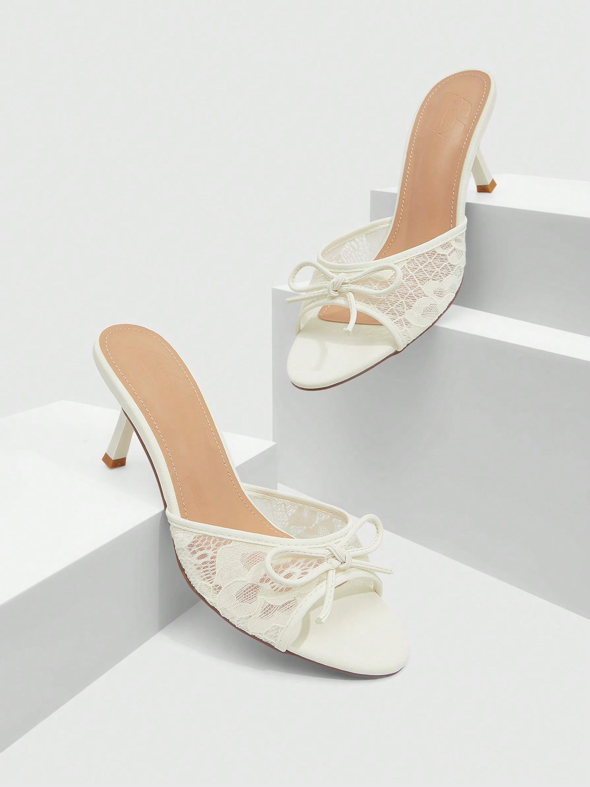 Open toe high heel slide sandals featuring lace details and a bow accent on the upper strap.