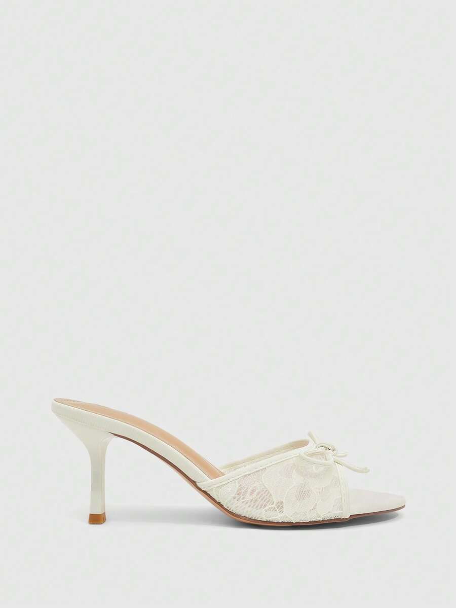Open toe high heel slide sandals featuring lace details and a bow accent on the upper strap.