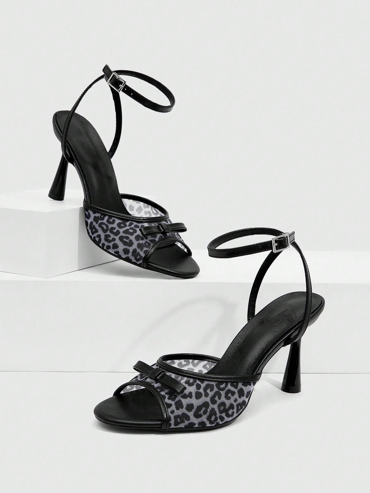 Pair of women's black high heel sandals with open toe design, slim stiletto heel, and adjustable ankle buckle strap.