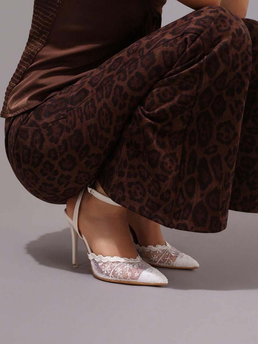 Lace embroidered high heels with thin stiletto heel, pointed toe, rhinestone embellishments, and ankle strap buckle closure.