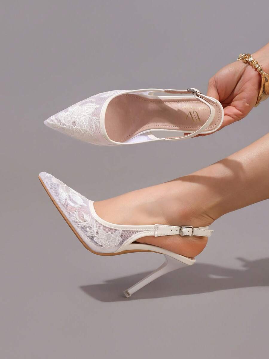 Lace embroidered high heels with thin stiletto heel, pointed toe, rhinestone embellishments, and ankle strap buckle closure.