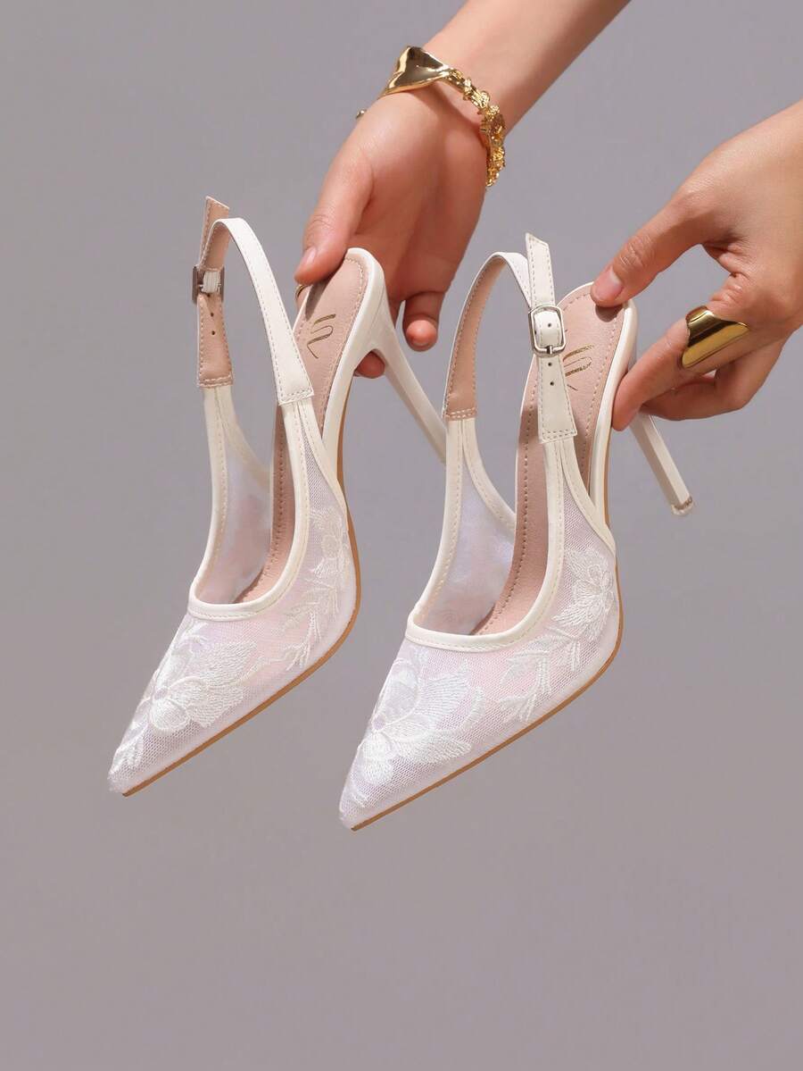 Lace embroidered high heels with thin stiletto heel, pointed toe, rhinestone embellishments, and ankle strap buckle closure.