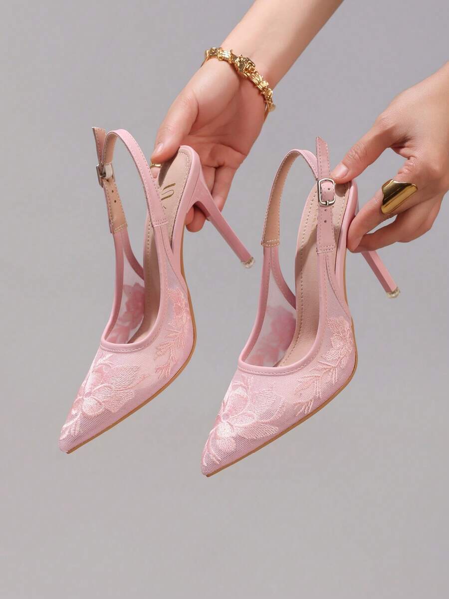 Lace embroidered high heels with thin stiletto heel, pointed toe, rhinestone embellishments, and ankle strap buckle closure.