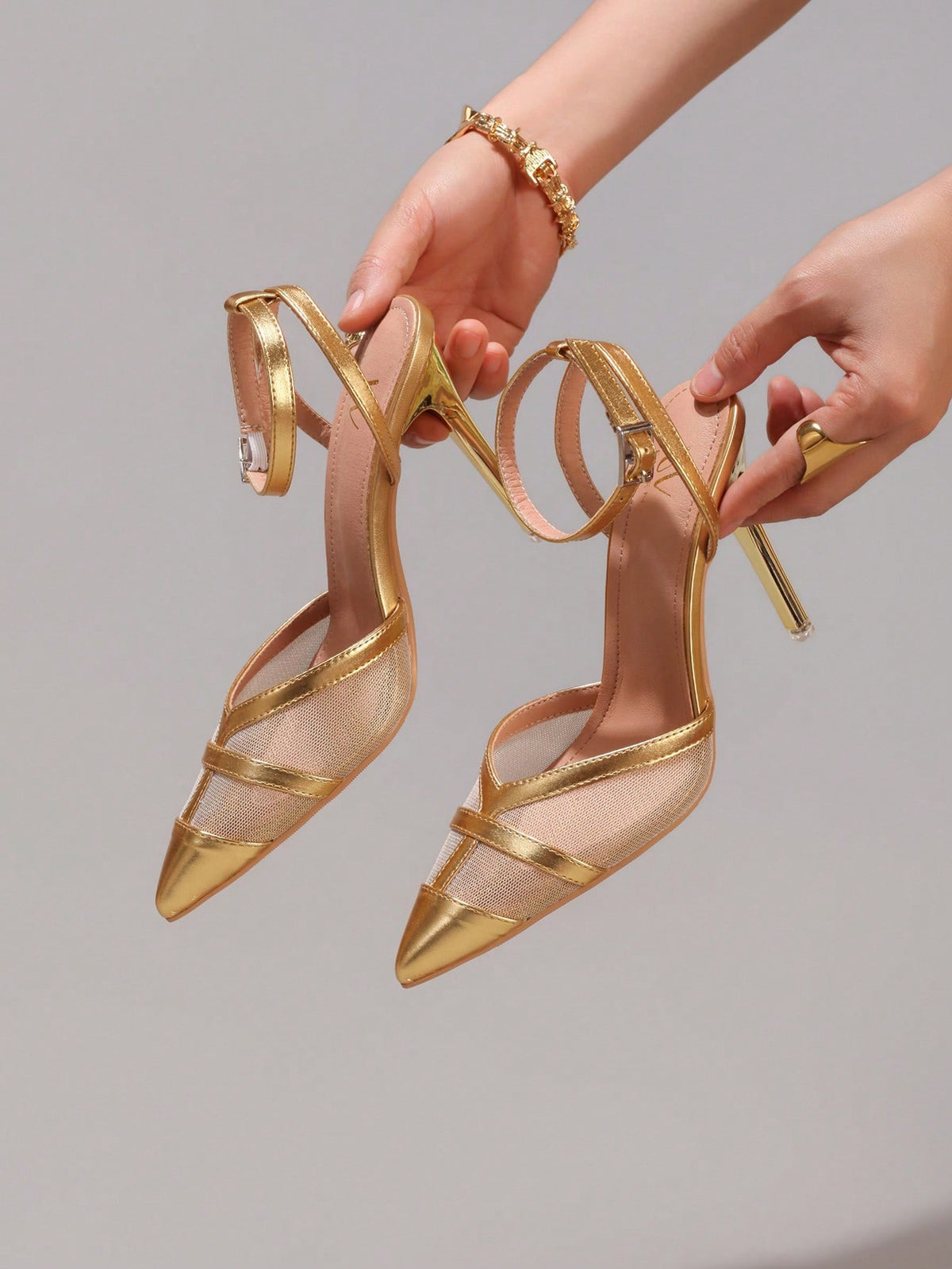 Lace embroidered high heels with thin stiletto heel, pointed toe, rhinestone embellishments, and ankle strap buckle closure.