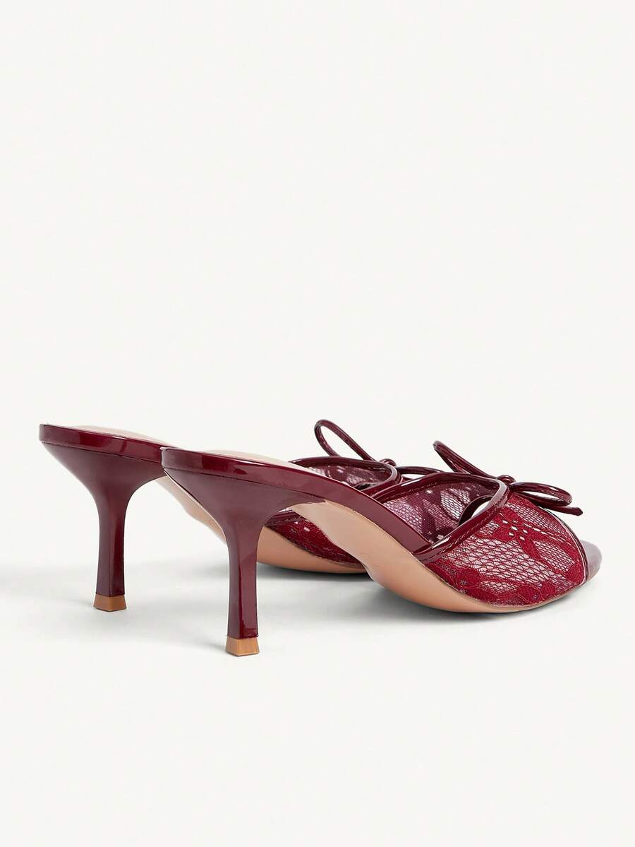 Open toe high heel slide sandals featuring lace details and a bow accent on the upper strap.