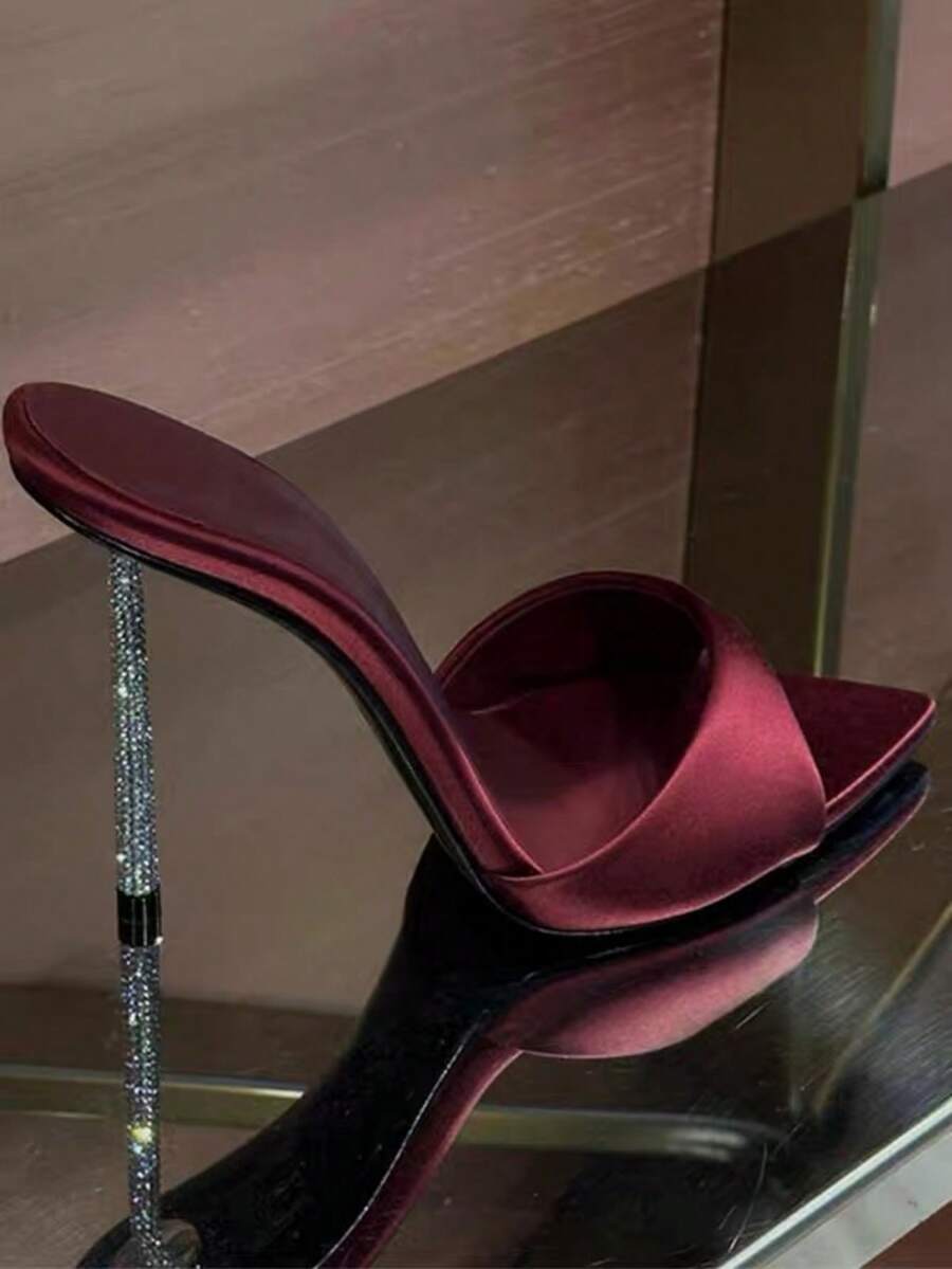 Women's black satin stiletto heeled sandals with sparkling rhinestone embellishments and a pointed peep toe design.