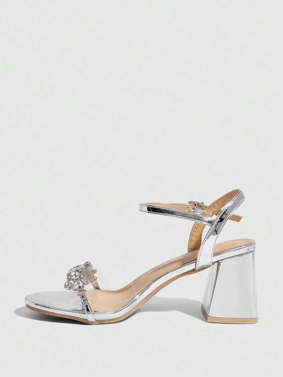 Pair of women's silver open-toe high-heeled sandals featuring sparkling rhinestone details, lace-up ankle straps, and a sturdy thick chunky heel.