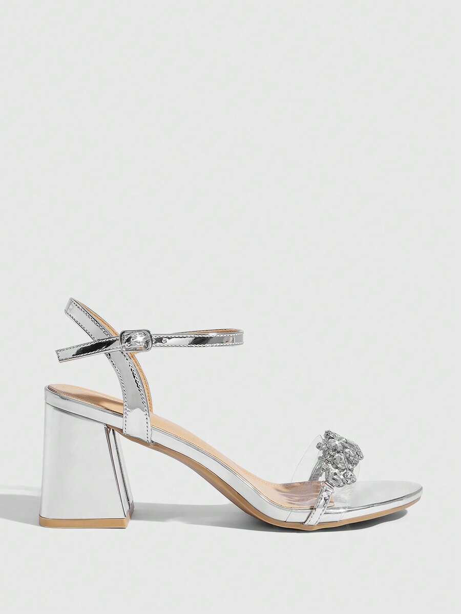 Pair of women's silver open-toe high-heeled sandals featuring sparkling rhinestone details, lace-up ankle straps, and a sturdy thick chunky heel.