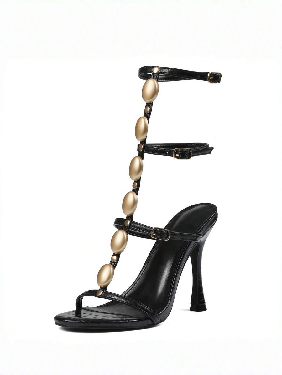 Women's black strappy gladiator sandals featuring pointed open toe, gemstone embellished woven ankle straps, and stiletto high heels.