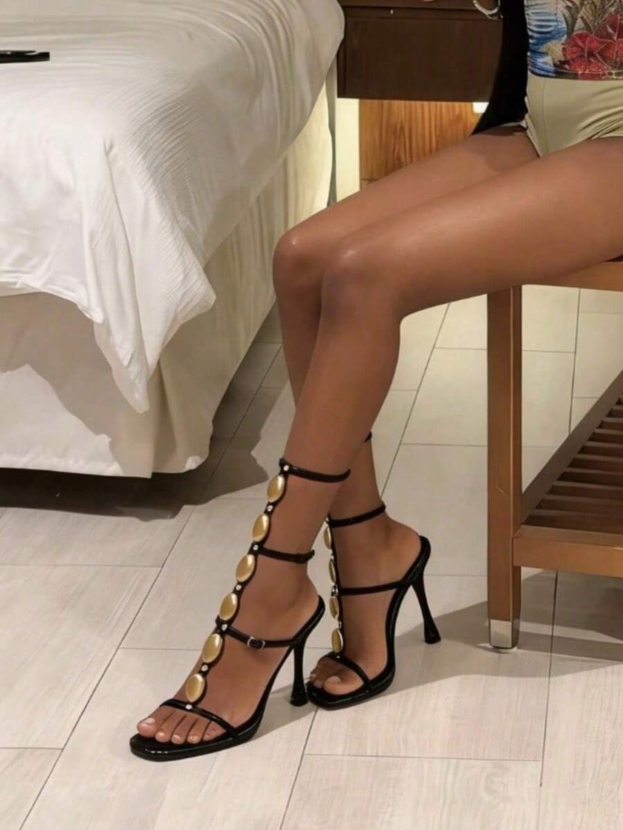 Women's black strappy gladiator sandals featuring pointed open toe, gemstone embellished woven ankle straps, and stiletto high heels.