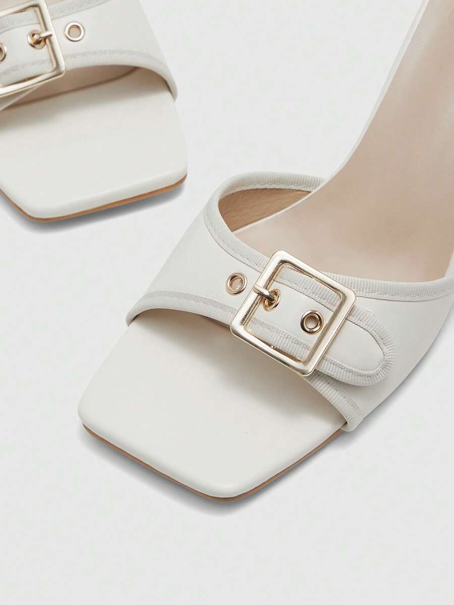 Beige women's slip-on kitten heel slide sandals featuring an accent buckle with grommet eyelets.