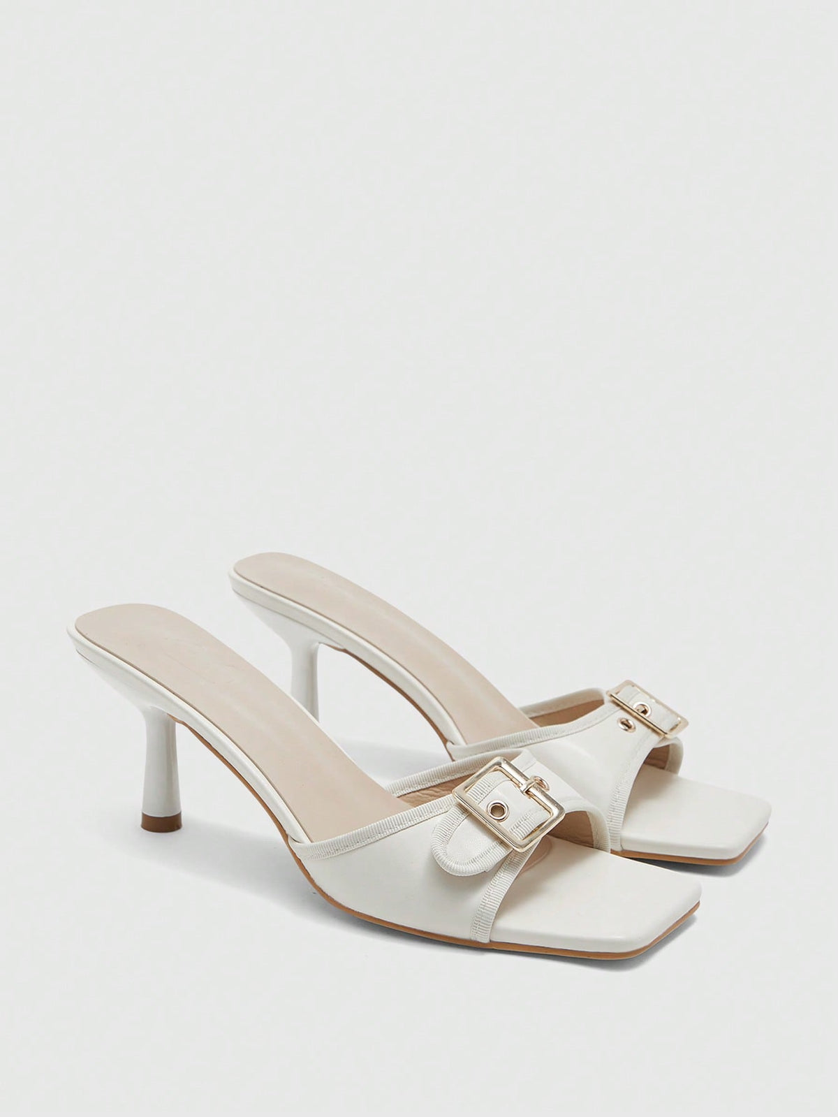 Beige women's slip-on kitten heel slide sandals featuring an accent buckle with grommet eyelets.