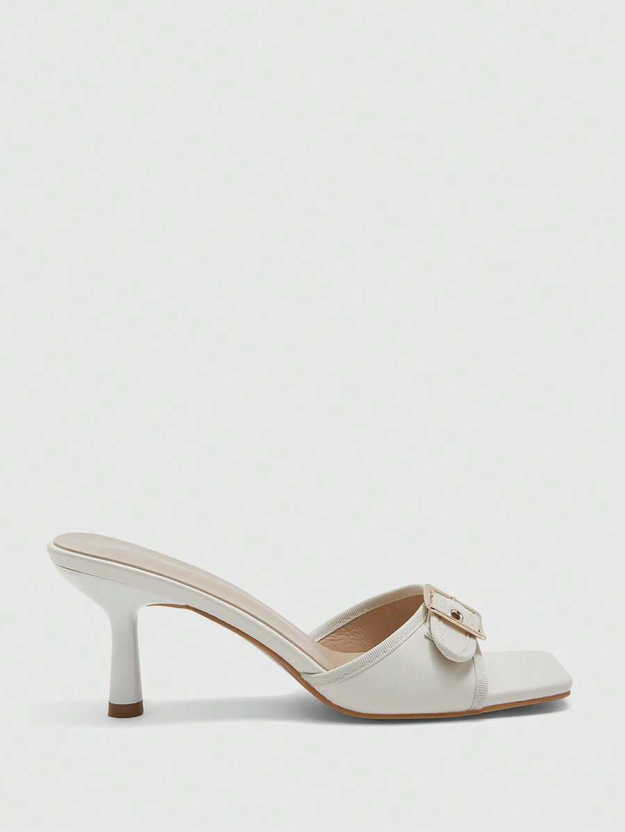Beige women's slip-on kitten heel slide sandals featuring an accent buckle with grommet eyelets.