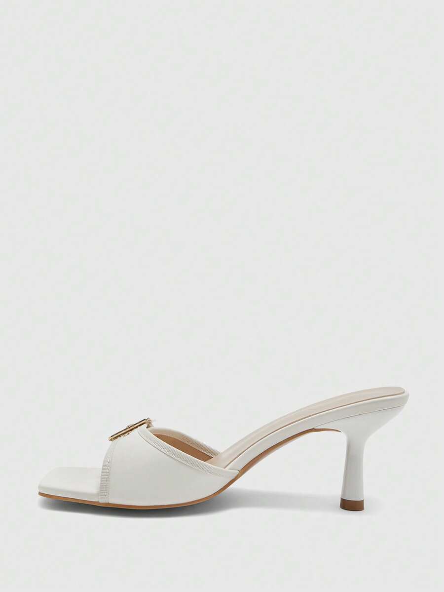 Beige women's slip-on kitten heel slide sandals featuring an accent buckle with grommet eyelets.