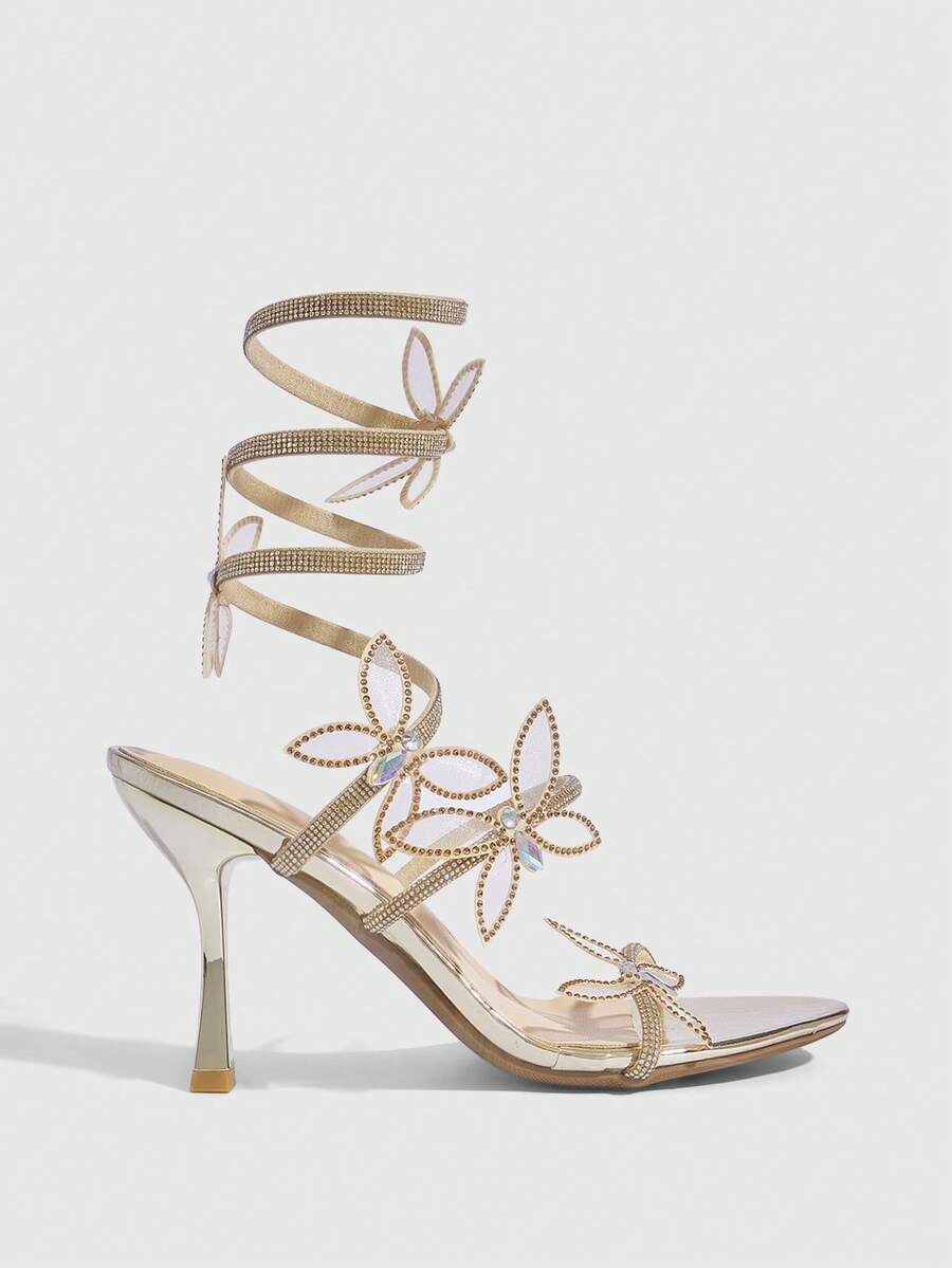 Gold stiletto high heel sandals with sparkling rhinestone bow accents and winding ankle straps for women