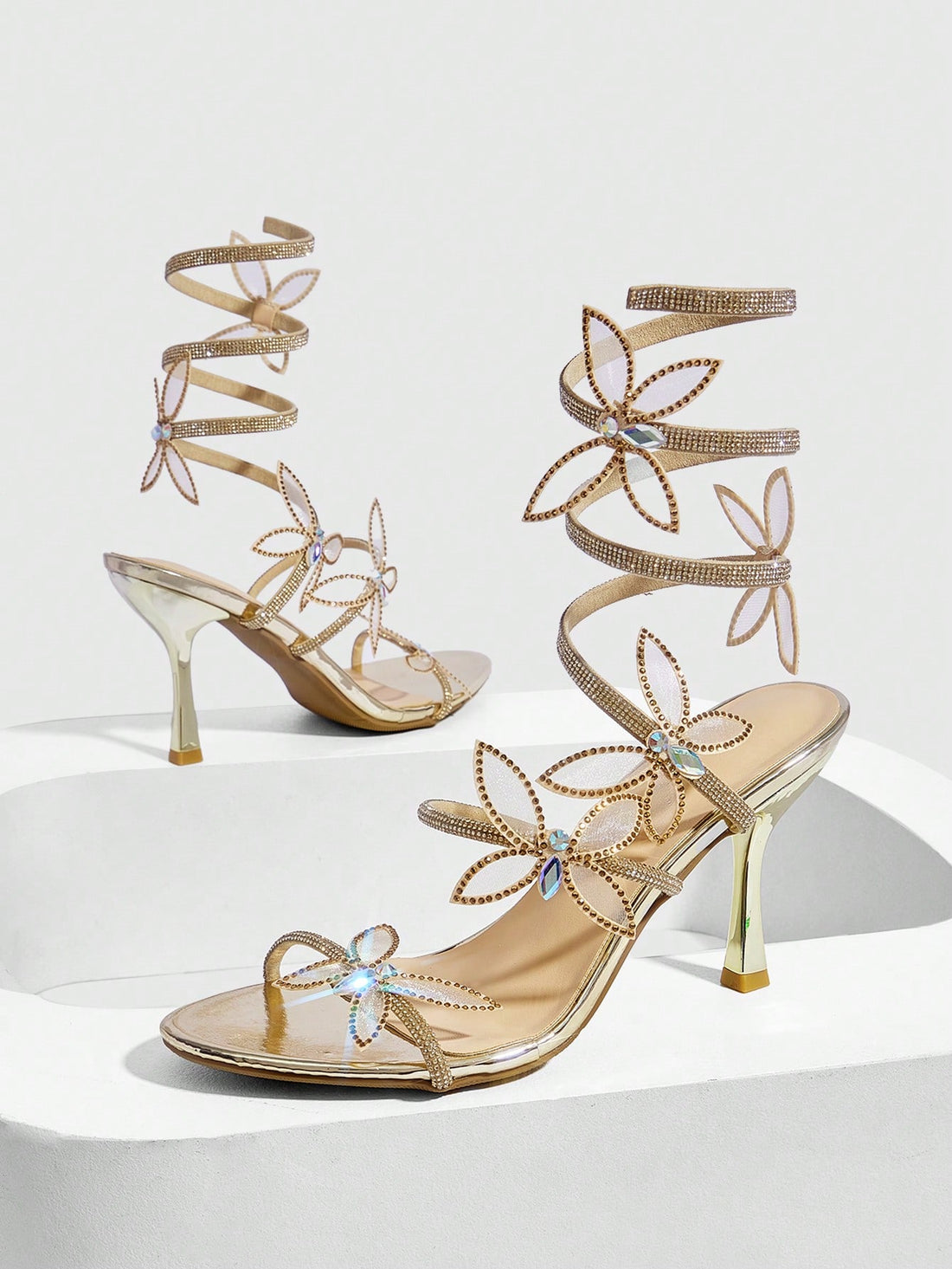 Gold stiletto high heel sandals with sparkling rhinestone bow accents and winding ankle straps for women